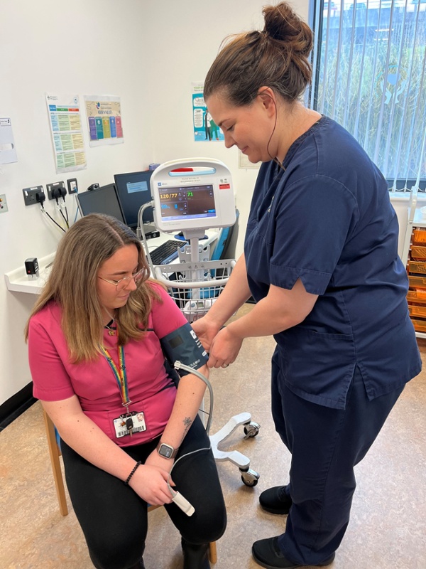 Image shows a staff member checking a colleague