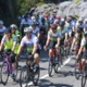 Image shows a large group of cyclists on a road.
