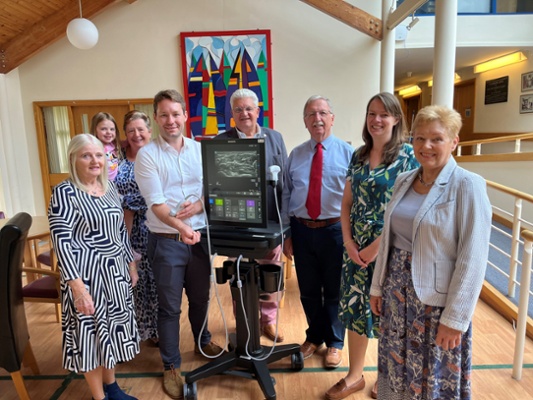 Image shows a group of people stood around a medical device