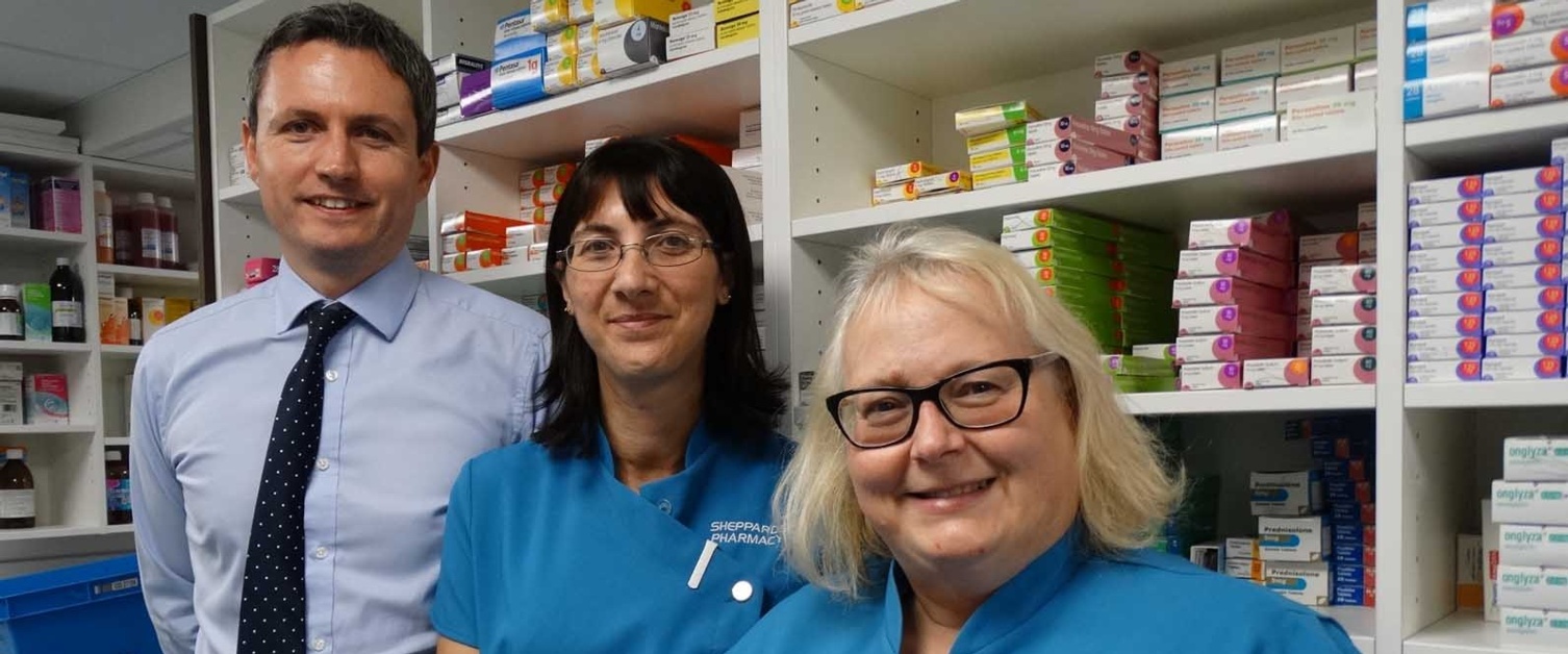 A pharmacist is pictured with two pharmacy assistants.