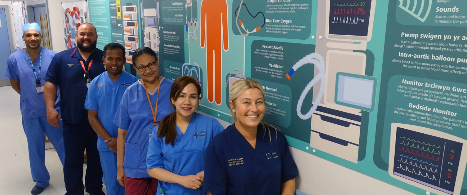 Image shows a group of staff alongside a corridor wall poster.