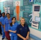 Image shows a group of staff alongside a corridor wall poster.