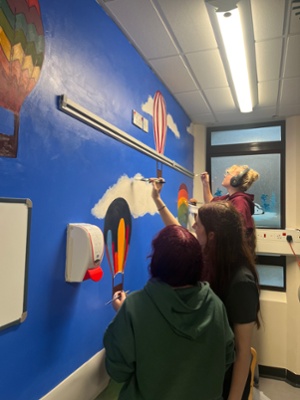 Image shows women painting a wall