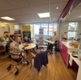 Image shows a woman playing a piano and people sitting at tables