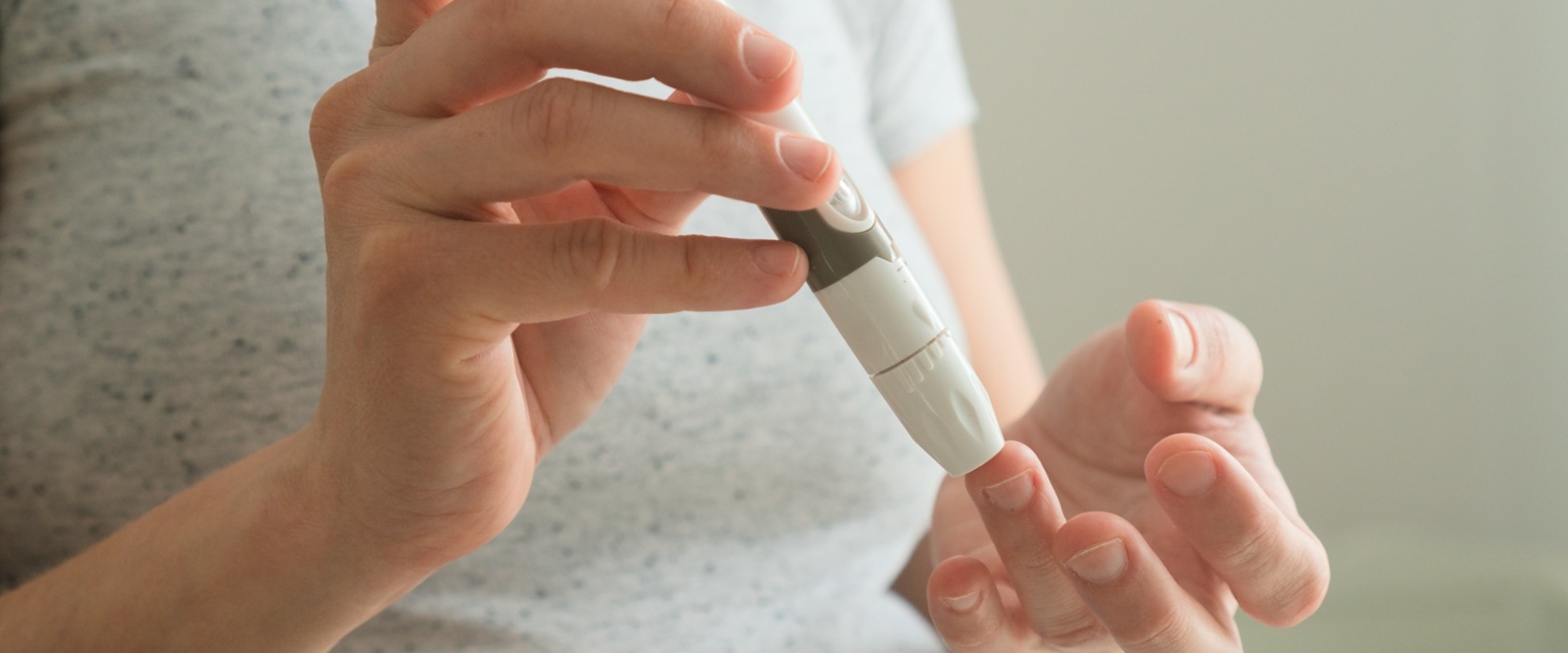 A pregnant woman takes a finger prick blood test to check glucose levels.