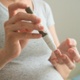 A pregnant woman takes a finger prick blood test to check glucose levels.