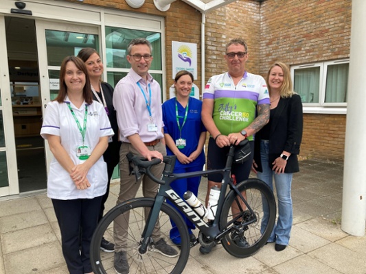 Image shows a group of people standing behind a bicycle