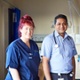A nurse, a doctor and another nurse stand on a hospital ward smiling at the camera.
