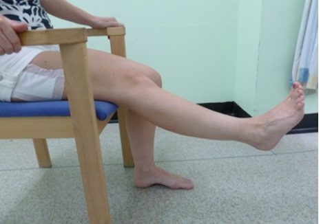 A patient is sitting on a chair. Their right leg is raised off the floor.
