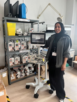Image shows a woman standing next to medical equipment