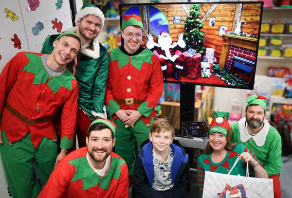 Image shows people dressed as elves with a young hospital patient.