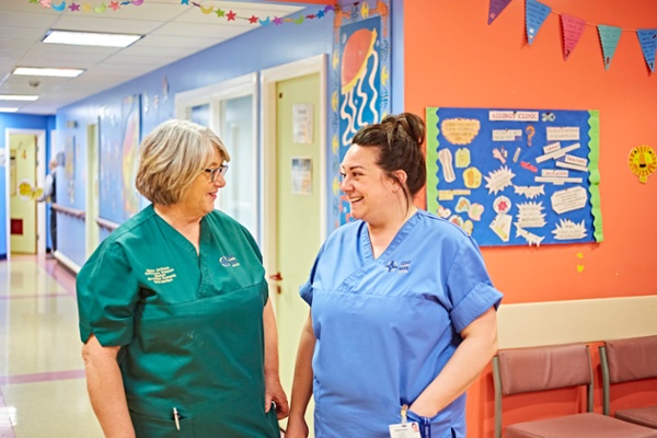 A healthcare support worker and nurse chat and smile.
