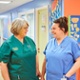 A healthcare support worker and nurse chat and smile.