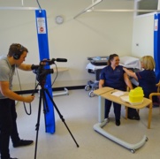 A photo of a nurse receiving her flu vaccination while being on film