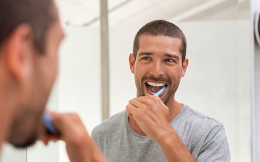 A man brushing his teeth in front of a mirror