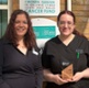 Image shows two women, one holding an award, outside a hospital.