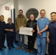 Rhodri and Wynne stand with the ITU team. They are holding a large cheque.