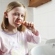 A young girl in her pyjamas brushing her teeth.
