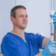 A male nurse taking liquid from a container with a syringe