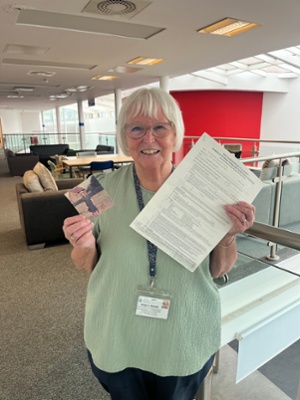 Image shows a woman holding a paper document