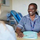A midwife smiles while talking to a patient on the other side of the desk.