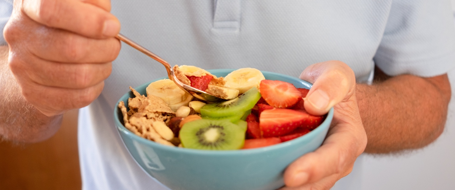 A man eating a bowl of fruit