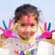 A child with paint over her hands and face.