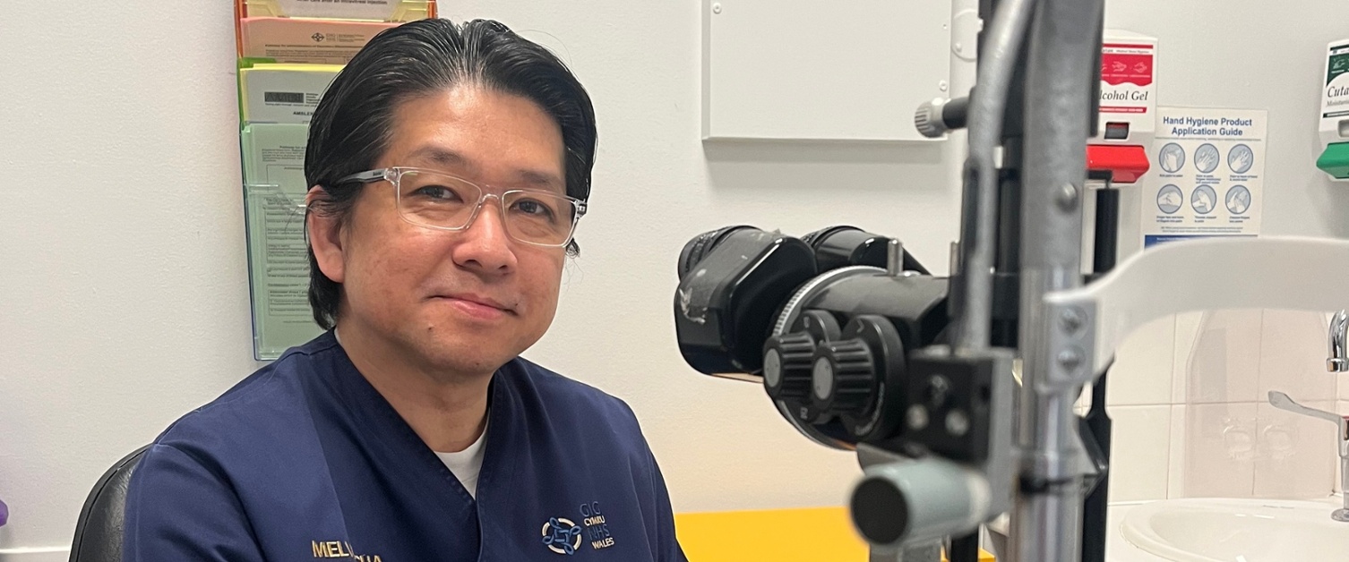 Image shows a man sitting next to a eye testing device