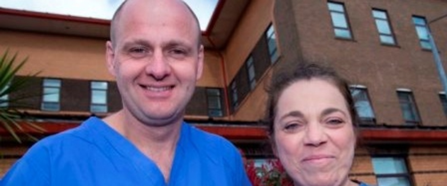 A man and a women,  David Johnston and Dominique Potokar, smiling at the camera outside Morriston Burns Centre.