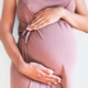 Image shows close up of pregnant woman with hands on her bump.