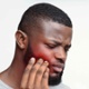 Image shows a man touching his jaw which is red to signify pain.