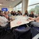 Image shows a group of people sat around a table