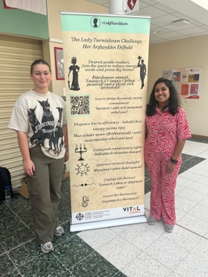 Image shows two women standing next to a banner