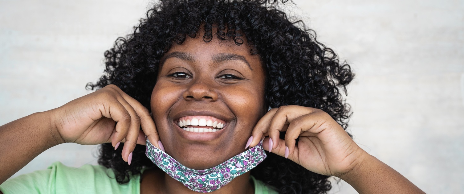 Close up of smiling woman who has pulled COVID face mask down to her chin.