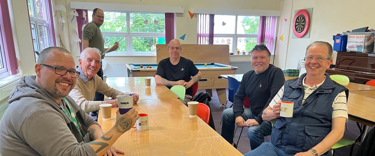 A group of men sat around a table holding mugs