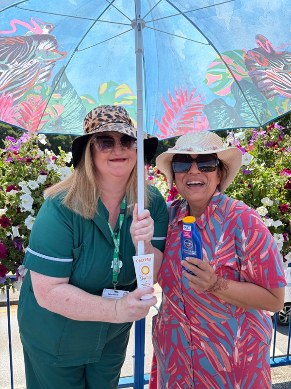 Hospital staff pictured sheltering under a parasol and holding sunscreen