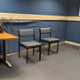 Image shows two grey chairs in front of a blue wall next to the audiologist desk.