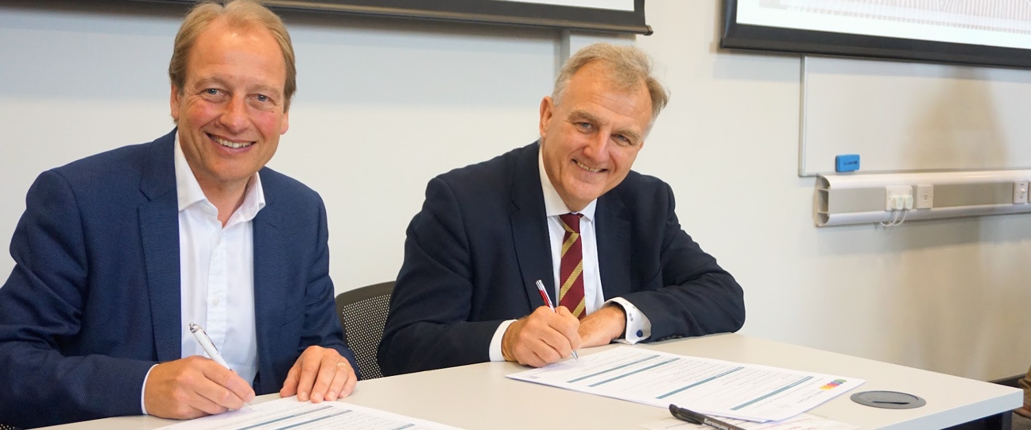 Image shows two men signing documents