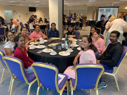 Image shows a group of people sat around a table