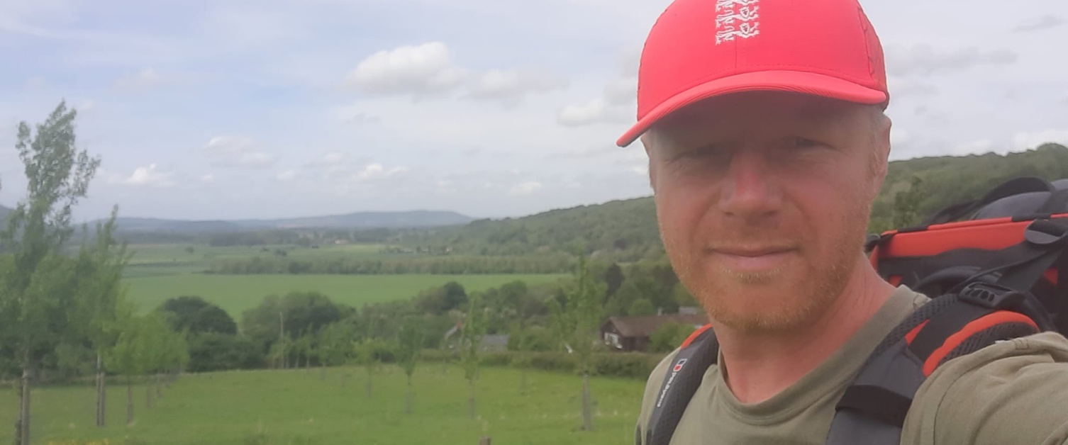 A man standing in a field wearing a red cap