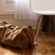 A brown bag placed on the wooden floor next to a white chair.