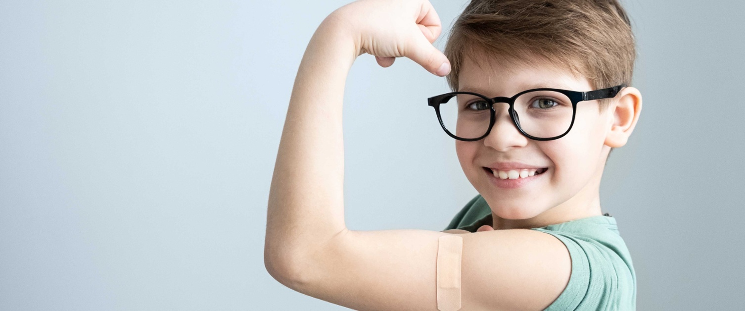Image shows boy wearing glasses holding up arm to show strength.