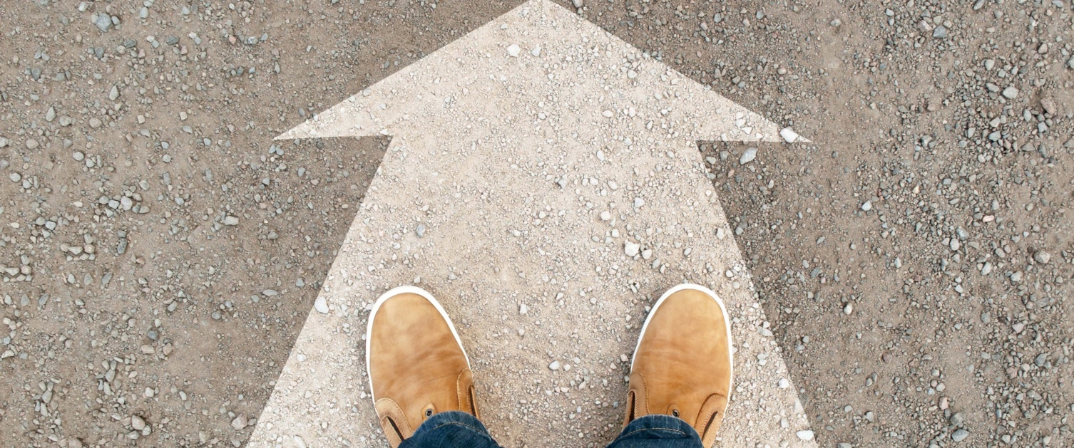 Image shows feet stood on large arrow painted on ground.