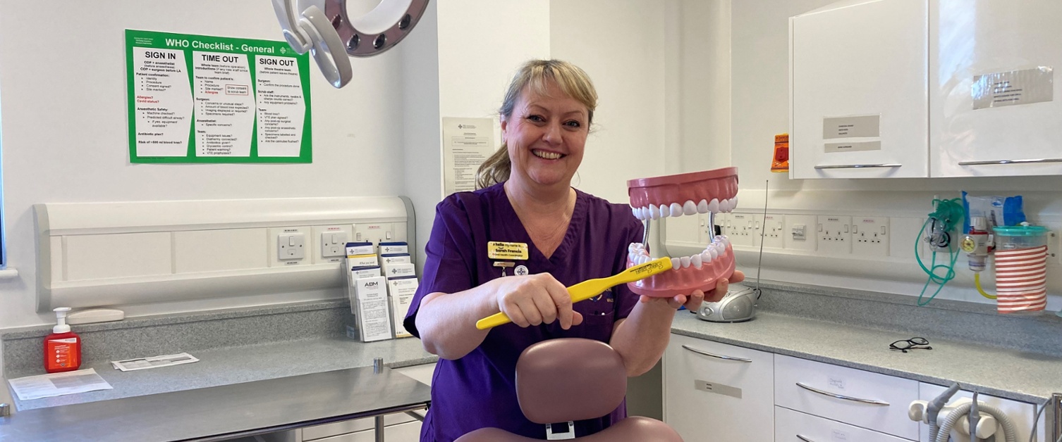 Image shows a woman holding a toothbrush and a set of dentures
