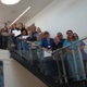 A large group of hospital staff holding certificates and standing on a staircase, smiling