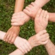 Image shows five hands clasped together in a circle.