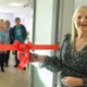 Image shows a woman cutting a ribbon to officially open a room.