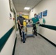 Image shows two men in a hospital corridor standing behind a machine and gas cylinder