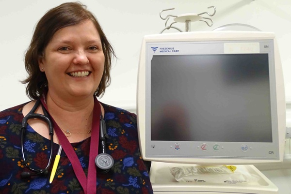 Image shows a doctor alongside a medical monitor.