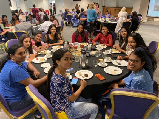 Image shows a group of people sat around a table